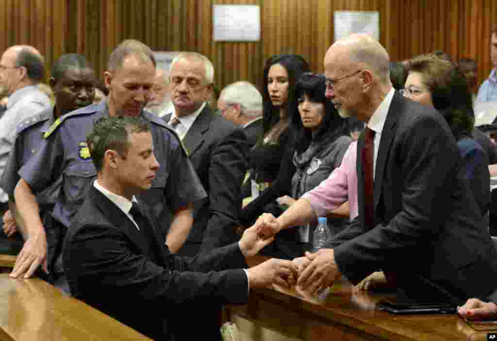 Oscar Pistorius, left front, greets his uncle Arnold Pistorius, right, and other family members as he is led out of court in Pretoria, South Africa. Pistorius received a five-year prison sentence for culpable homicide by Judge Thokozile Masipa.