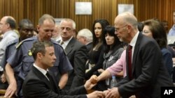 Oscar Pistorius, à gauche, salue son oncle Arnold Pistorius, à droite, et les autres membres de sa famille à Pretoria, en Afrique du Sud, le 21 octobre 2014. 