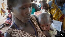 FILE - In this photo taken Friday, Sept. 16, 2016, Elizabeth Athiel holds her 8-month-old malnourished daughter Anger, at a UNICEF feeding center in Aweil, South Sudan.