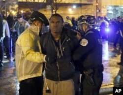 Two Chicago police officers take a man into custody during a protest march, Wednesday, Nov. 25, 2015, in Chicago, the day after murder charges were brought against police officer Jason Van Dyke in the killing of 17-year-old Laquan McDonald.