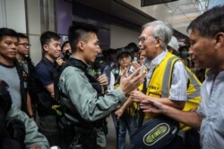 "Grandpa Wong," 85, speaks with a riot police officer along with other "silver hair" volunteers in the Tung Chung district in Hong Kong, Sept. 7, 2019.