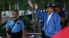 Escoltado por uno de sus guardias de seguridad armados, Daniel Ortega, a la derecha, saluda a una multitud de fieles del partido durante una marcha por la paz, en Managua, Nicaragua, el 7 de julio de 2018. 