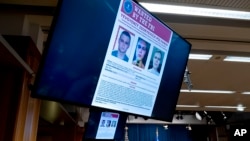 Russian Yevgeniy Polyanin, wanted by the FBI, is displayed on monitors at the Justice Department in Washington, Nov. 8, 2021.