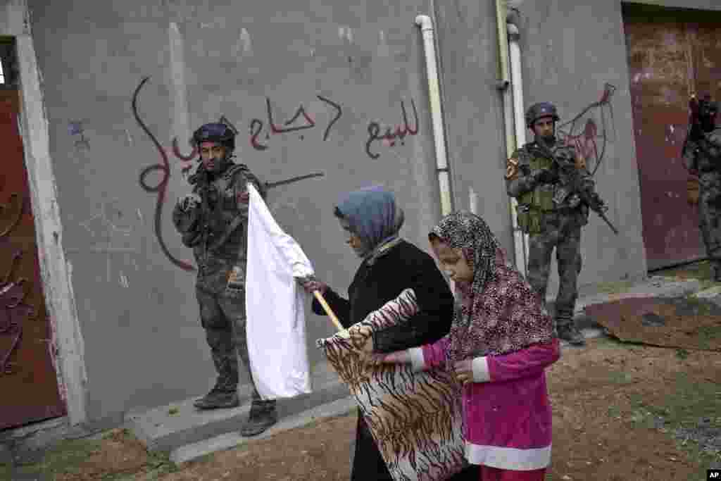 Civilians carry a white flag as they pass Iraqi special forces on patrol in Gogjali, an eastern district of Mosul, Iraq.