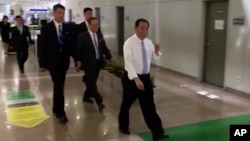 In this image made from video, Kim Yong Chol, in white, a former military intelligence chief who is now Kim Jong Un's top official on inter-Korean relations, walks upon arrival at Beijing airport in Beijing, May 29, 2018. 