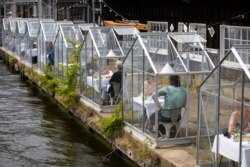 FILE - Customers eat lunch in small glass houses at the Mediamatic restaurant in Amsterdam, Netherlands, June 1, 2020.