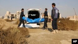 This frame grab from a video provided on Nov. 22, 2018, shows Syrian workers of a Raqqa group carrying human remains at the site of a mass grave believed to contain the bodies of civilians and Islamic State militants, in Raqqa. 