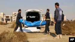 FILE - This frame grab from a video provided on Nov. 22, 2018, shows Syrian workers of a Raqqa group carrying human remains at the site of a mass grave believed to contain the bodies of civilians and Islamic State militants, in Raqqa. 