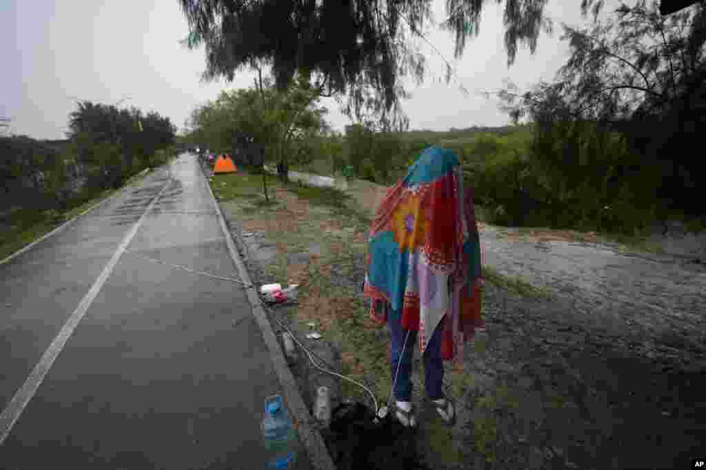 Un migrante venezolano cubierto con una manta envía mensajes de texto, a orillas del Río Grande en Matamoros, México, el sábado 13 de mayo de 2023. La imagen describe parte de la dura travesía de quienes se aventuran a llegar a EEUU atravesando fronteras en la región. ]Foto: Fernando Llano]