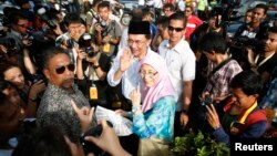 Pemimpin oposisi Malaysia Anwar Ibrahim dan istrinya Wan Azizah Wan Ismail meninggalkan TPS pasca memilih dalam pemilu nasional Malaysia di Permatang Pauh, Malaysia (5/5). Kepolisian Malaysia mengancam akan menangkap orang-orang yang ikut aksi demo tanpa izin untuk memprotes hasil pemilu.