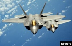 FILE - Two U.S. Air Force F-22 Raptor stealth jet fighters fly near Andersen Air Force Base.