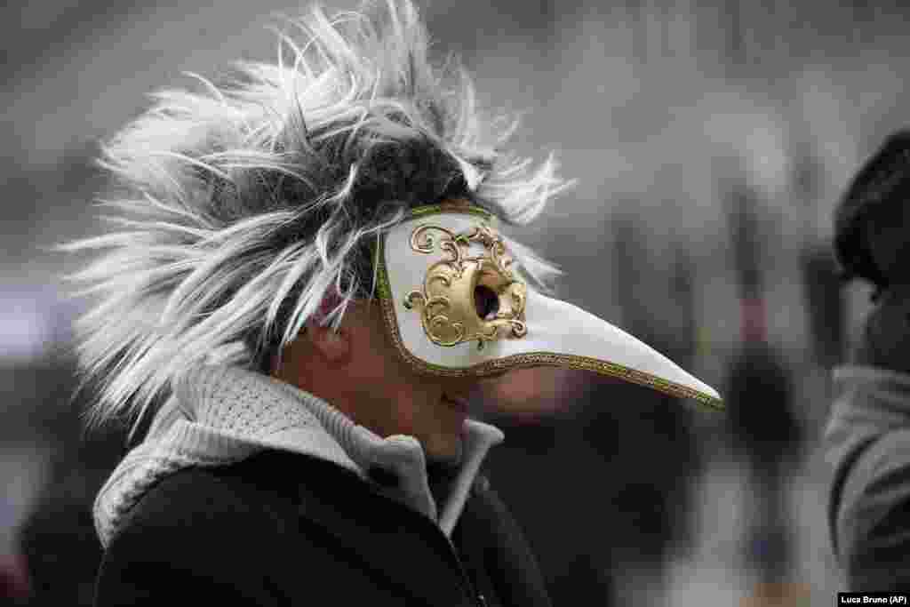 A man wearing a bird mask walks in Saint Mark&#39;s Square in Venice, Italy at the start of Carnival.