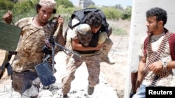 A fighter of Libyan forces allied with the U.N.-backed government runs for cover with another fighter while carrying a wounded fighter during a battle with Islamic State fighters in Sirte, Libya, July 31, 2016. 