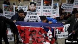 FILE - Protesters tear a defaced North Korean flag during an anti-North Korean rally in central Seoul, South Korea, Nov. 23, 2015. In the wake a group defection by 13 North Koreans, South Korea has warned its citizens of a hightned threat of abductions by