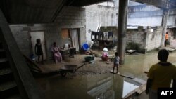 Des habitants se rassemblent dans la zone d'habitation en partie inondée à l'intérieur du Centre international des civilisations bantoues (CICIBA), dans la commune d'Akanda, près de la capitale gabonaise Libreville, le 9 octobre 2021.