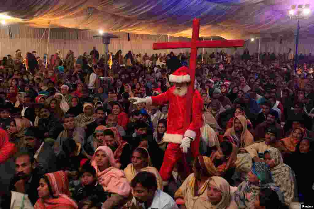 پاکستان کے شہر لاہور کے ایک گرجا گھر میں موجود مسیحی برادری کے افراد دعائیہ تقریب میں شریک ہیں جب کہ انہی میں موجود سانتا کلاز اپنے کاندھے پر صلیب اٹھائے ہوئے ہے۔