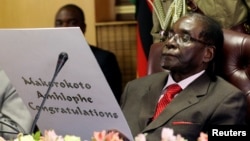 Zimbabwe's President Robert Mugabe reads a card during his 93rd birthday celebrations in Harare, Feb. 21, 2017. 
