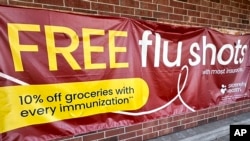 FILE - A sign for flu vaccination is displayed outside of a grocery store in Glenview, Illinois, Feb. 15, 2024.