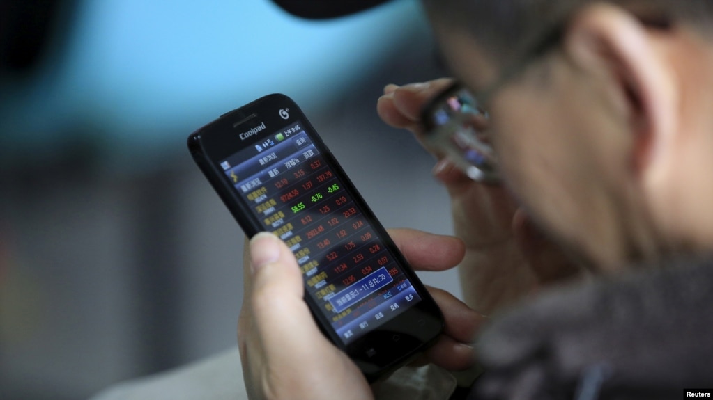 资料:一投资者在上海一家经纪行用手机查看股票信息(2016年3月7日)