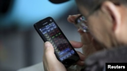 资料：一投资者在上海一家经纪行用手机查看股票信息（2016年3月7日）