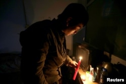 Migrant worker Chen Shuang lights a candle at an apartment where, according to manager of the building, security guards of the village cut off the power lines, at Xinjiancun, in Picun village on the outskirts of Beijing, China, Nov. 19, 2017.