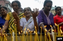 Sri Lankan Christian devotees light candles as they pray at a barricade near St. Anthony's Shrine in Colombo, April 28, 2019, a week after a series of bomb blasts targeting churches and luxury hotels on Easter Sunday in Sri Lanka.
