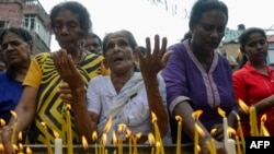 FILE - Sri Lankan Christian devotees light candles as they pray at a barricade near St. Anthony's Shrine in Colombo, Apr. 28, 2019, a week after a series of bomb blasts targeting churches and luxury hotels on Easter Sunday.