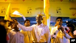 Maldives' opposition presidential candidate Ibrahim Mohamed Solih, center, shakes hands with a supporter as his running mate, Faisal Naseem, right, addresses the gathering in Male, Maldives, Monday, Sept. 24, 2018.
