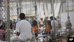 ARCHIVO - En esta fotografía proporcionada por la Oficina de Aduanas y Protección Fronteriza, varias personas detenidas en casos de ingreso ilegal a Estados Unidos permanecen sentadas en un recinto enrejado de unas instalaciones, el 17 de junio de 2018, en McAllen, Texas.