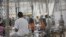 ARCHIVO - En esta fotografía proporcionada por la Oficina de Aduanas y Protección Fronteriza, varias personas detenidas en casos de ingreso ilegal a Estados Unidos permanecen sentadas en un recinto enrejado de unas instalaciones, el 17 de junio de 2018, en McAllen, Texas.