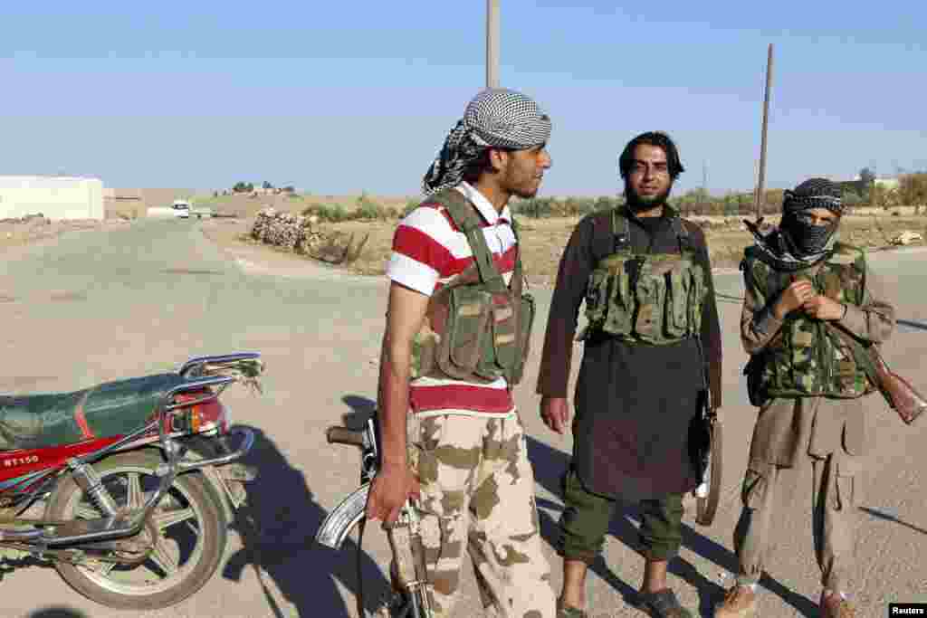 Islamic State fighters stand along a street in the countryside of the Syrian Kurdish town of Kobani, Oct. 7, 2014.