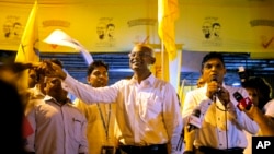 Maldives' opposition presidential candidate Ibrahim Mohamed Solih, center, shakes hands with a supporter as his running mate, Faisal Naseem, right, addresses the gathering in Male, Maldives, Monday, Sept. 24, 2018.