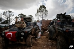 FILE - A Turkish soldier waves sitting atop a military vehicle at Bursayah Hill in the greater Afrin district, Syria, during a Turkish government-organized media tour in northern Syria, March 3, 2018.