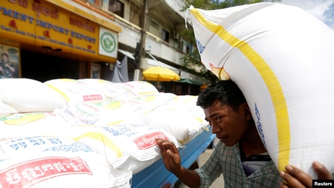 一名柬埔寨男子在金边的一辆卡车旁扛起一袋大米。（2017年7月12日）