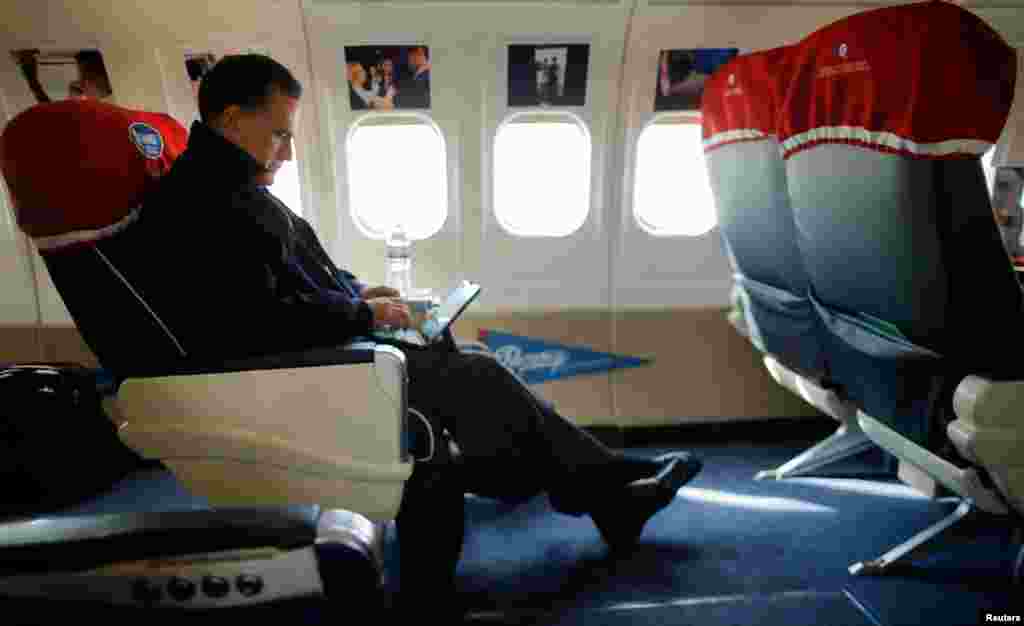 Mitt Romney looks at his iPad on his campaign plane en route to North Canton, Ohio October 26, 2012. 