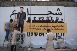 FILE - An Afghan artist paints a mural with the image of slain Agence France-Presse photographer Shah Marai, who was killed along with other Afghan journalists in a targeted suicide bombing, in Kabul, Sept. 25, 2018.