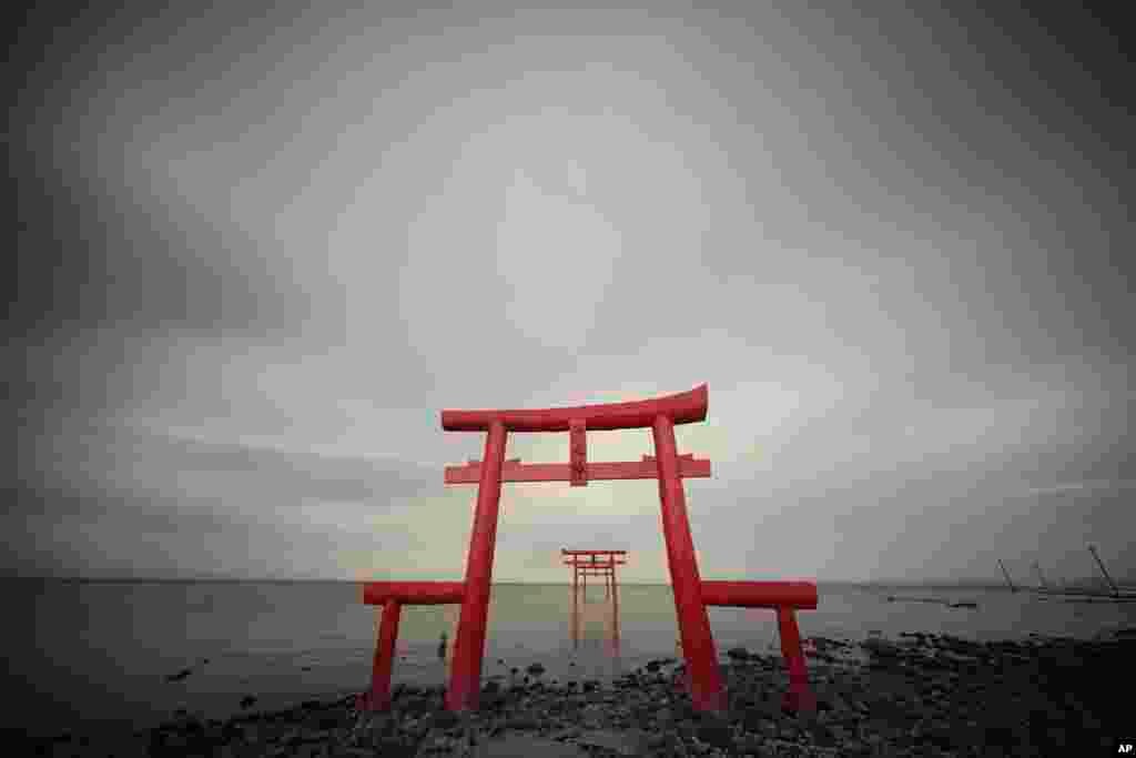 Lengkungan kuil kecil atau gerbang &quot;Torii&quot; berdiri di pantai menghadap ke Laut Ariake di Tara, Prefektur Saga, barat daya Jepang.