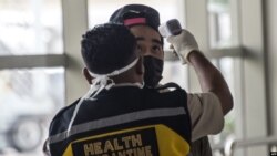 Seorang petugas memeriksa seorang penumpang yang tiba di Bandara Internasional Juanda di Sidoarjo, Jawa Timur, 30 Januari 2020. (Foto: AFP)