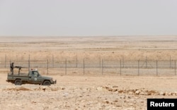 FILE - A military truck belonging to the Saudi border guards force patrol near a fence on Saudi Arabia's northern borderline with Iraq.