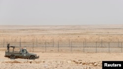 FILE - A military truck belonging to the Saudi border guards force patrol near a fence on Saudi Arabia's northern borderline with Iraq.