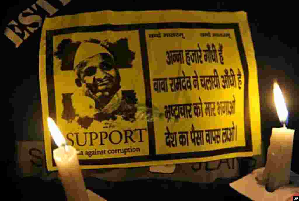 A supporter of Indian social activist Anna Hazare holds lit the candles and a Hazare sticker during a protest in New Delhi on August 17, 2011. (AFP)