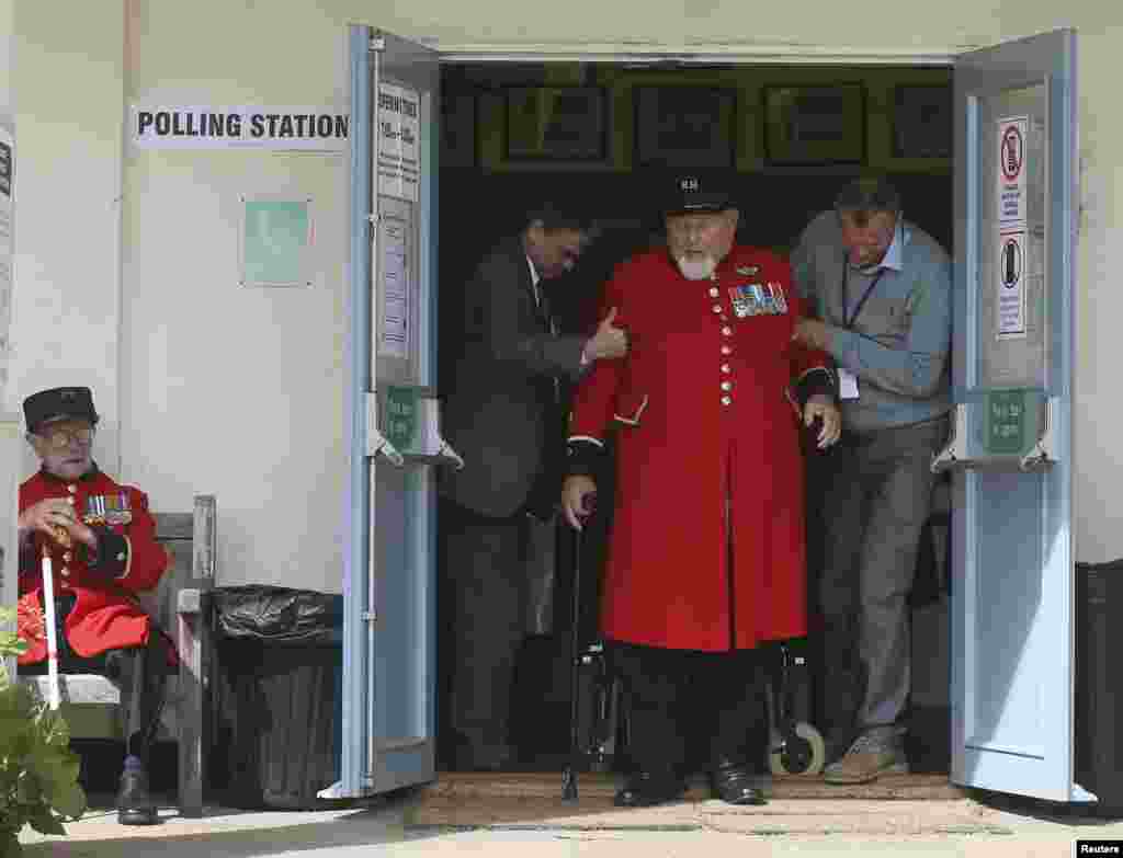Chelsea Pensioner Wayne Campbell is helped out of a polling station after casting his vote in the general election, London, May 7, 2015.