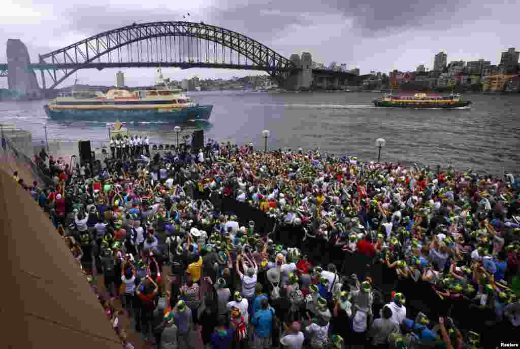 Members of the Australian cricket team wave to passengers sailing past on ferries during a public celebration ceremony at the Sydney Opera House.