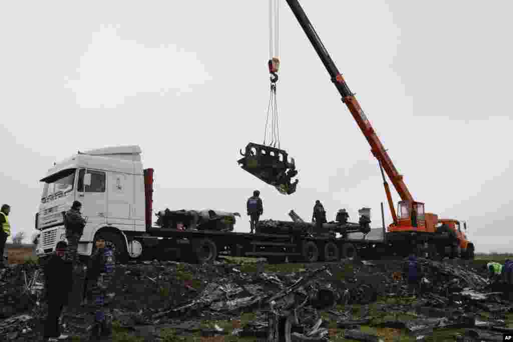 Para pekerja lokal mengangkat puing-puing pesawat Malaysia Airlines MH17 dekat daerah permukiman Grabovo, Donetsk, Ukraina timur (16/11).&nbsp;&nbsp;(AP/Mstyslav Chernov)