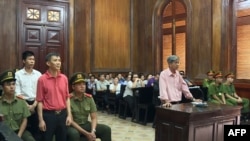 Michael Phuong Minh Nguyen, third from left, stands during his trial, June 24, 2019, in Ho Chin Minh City, Vietnam. The American of Vietnamese origin was sentenced to 12 years in prison for "attempt to overthrow the state." 