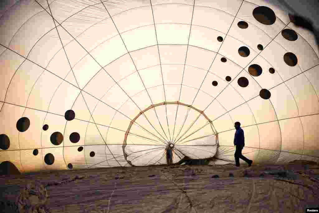 A crew member inspects a partially inflated hot air balloon at the Bristol International Balloon Fiesta in Bristol, Britain.