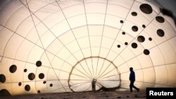 A crew member inspects a partially inflated hot air balloon at the Bristol International Balloon Fiesta in Bristol, Britain.