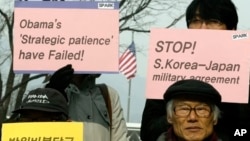 Protesters hold placards during denouncing military alliance between South Korea, the United States and Japan, Seoul, Jan. 15, 2013.