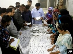 Pakistani election staff count the votes after polls closed at a polling station for the parliamentary elections in Karachi, Pakistan, July 25, 2018.