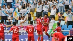 인천 아시안게임에 출전한 북한 남자 축구 대표팀 선수들이 중국과의 첫 경기에서 득점을 올린 후 환호하고 있다. 뒷쪽으로 이들을 응원하는 한국 응원단의 모습이 보인다. 북한은 중국에 3:0으로 완승을 거뒀다.